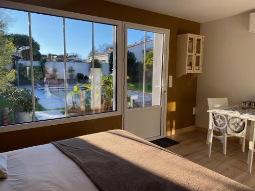 a bedroom with a bed and a large window at Maison M, chambre privée accès jardin piscine et jacuzzi près de La Rochelle in La Rochelle