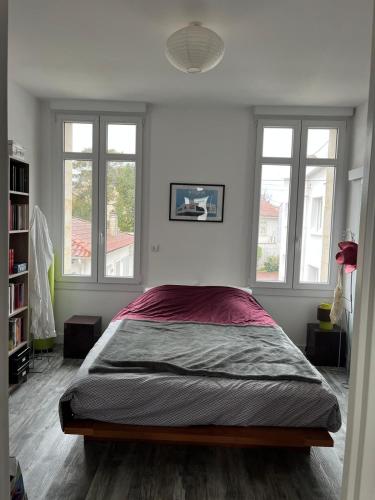 - une chambre avec un grand lit dans une pièce dotée de fenêtres dans l'établissement Très bel appartement avec grande terrasse 300m de la plage, à Royan