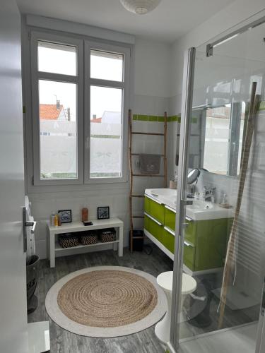La salle de bains est pourvue d'un lavabo vert et d'une douche. dans l'établissement Très bel appartement avec grande terrasse 300m de la plage, à Royan
