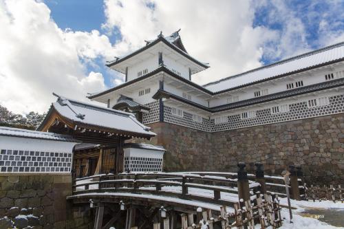 a large building with snow on the ground at HOTEL AO Kanazawa in Kanazawa
