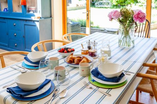 a table with plates of food and a vase of flowers at Barton Cottage Bed and Breakfast in Broadmayne