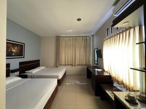 a hotel room with two beds and a window at Hotel Century Pangandaran in Pangandaran