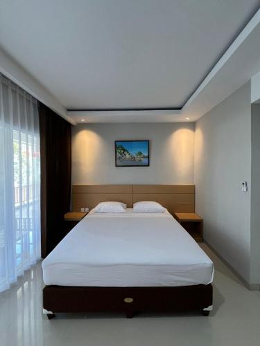a bedroom with a large white bed in a room at Hotel Century Pangandaran in Pangandaran