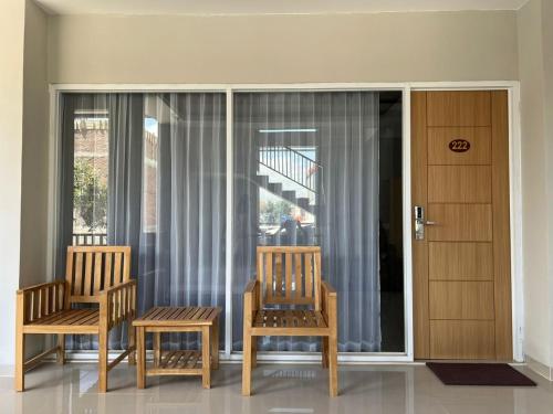 two chairs and a table in a room with windows at Hotel Century Pangandaran in Pangandaran
