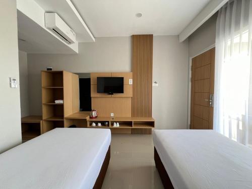 a bedroom with two beds and a television in it at Hotel Century Pangandaran in Pangandaran