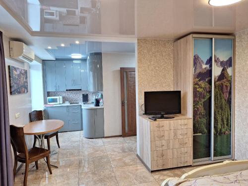 eine Küche mit einem Tisch und einem TV in einem Zimmer in der Unterkunft 1-комнатная на левом берегу Днепра in Dnipro
