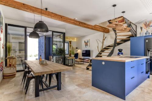 une cuisine avec un îlot bleu et un escalier dans l'établissement La Remise des Amis - Proche du centre du village, à Peyriac-de-Mer