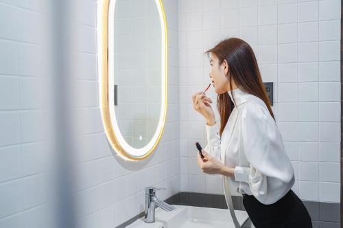a woman brushing her teeth in front of a mirror at Nature Hotel - Win Happy in Da Lat