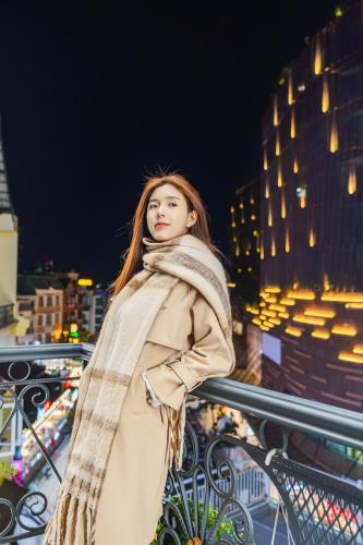 a woman standing on a balcony at night at Nature Hotel - Win Happy in Da Lat