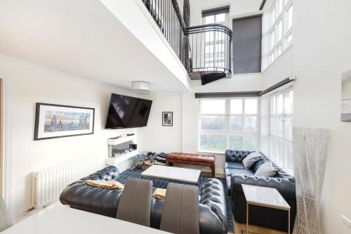 a living room with a couch and a tv at JOIVY Stylish 3 bed, 3 bath flat with Balcony in Old Town in Edinburgh