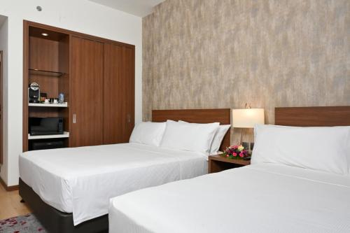 two beds in a hotel room with white sheets at Comfort Hotel Riyadh Olaya in Riyadh