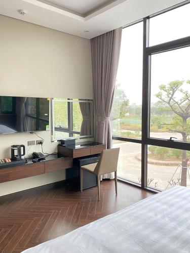 a bedroom with a desk and a bed and a window at Kings Villa in Gio Nhan