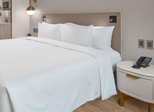 a hotel room with a white bed and a telephone at Lanson Place Mall of Asia Manila in Manila