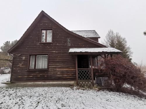 a wooden house with snow on the ground at Dwór w Zabużu in Zabuże