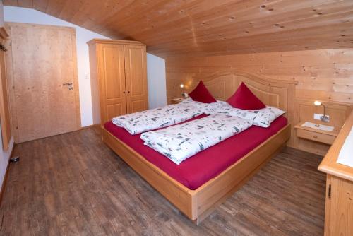 a bedroom with a large bed with red pillows at Chalet Innertal in Inneralpbach