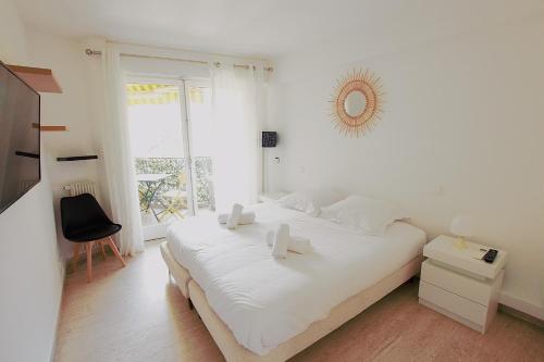 une chambre blanche avec un grand lit blanc et une fenêtre dans l'établissement Cannes Palm Beach - Fully fitted apartment - 2 bedrooms, à Cannes
