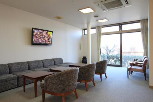 a living room with a couch and a table and chairs at 尾道やすらぎの宿しーそー in Onomichi