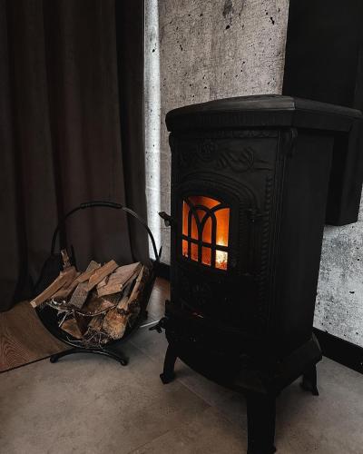 a black stove with a pile of wood in a room at Domki Fajnie.Tu in Łączna