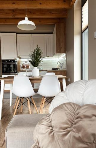 a kitchen with a table and white chairs in a room at Domki Fajnie.Tu in Łączna