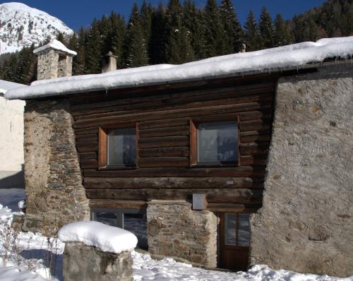 a log cabin with snow on top of it at Charming 3½ room cottage in Valposchiavo in Poschiavo