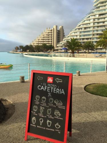 a chalkboard sign next to a body of water with buildings at Condominio San Alfonso del Mar in Algarrobo