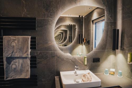 a bathroom with a sink and a mirror at Dilly - Das Nationalpark Resort in Windischgarsten