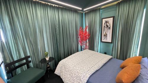 a bedroom with green curtains and a bed and a chair at Luxury Elite Apartment with Exclusive Views in Lahore