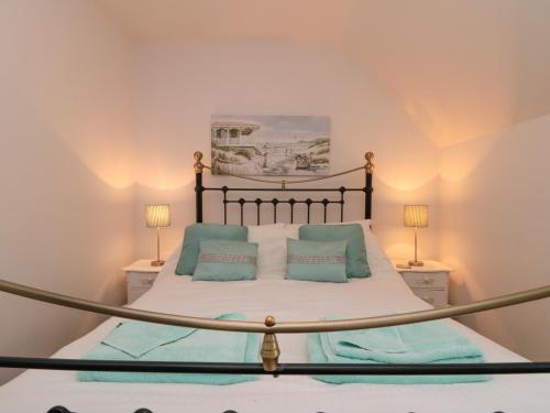 a bedroom with a large bed with blue pillows at Dotty's Sunshine Cottage in Reighton