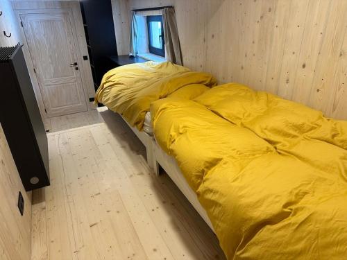 a bed with a yellow comforter in a room at Le Randonneur charmful chalet near Zermatt 6 to 12p in Täsch