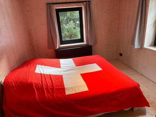 a bed with a red blanket with a white cross on it at Le Randonneur charmful chalet near Zermatt 6 to 12p in Täsch