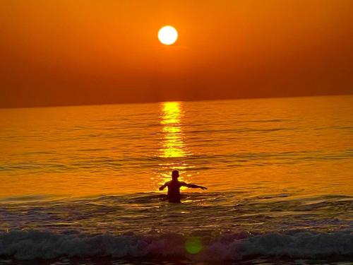 a man standing in the ocean watching the sunset at Poco Loco B&B in Abene