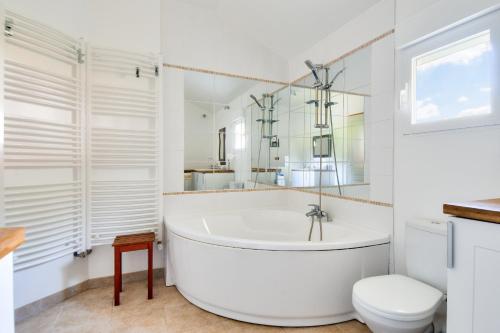 a white bathroom with a tub and a toilet at Face à l'océan, belle maison spacieuse pour 6 in Préfailles