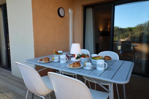 een blauwe tafel met borden met voedsel erop bij La Parenthèse Corse - T2 cabine vue mer in Pianottoli-Caldarello