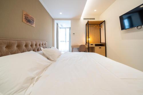 a bedroom with a white bed with a flat screen tv at MERKO HOTEL in Berat