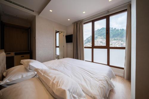 a bedroom with a white bed with a large window at MERKO HOTEL in Berat