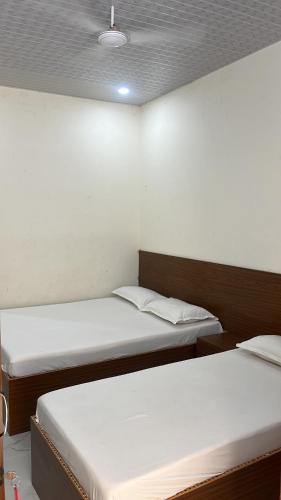 two beds in a room with white walls at Svr guest house in Puttaparthi