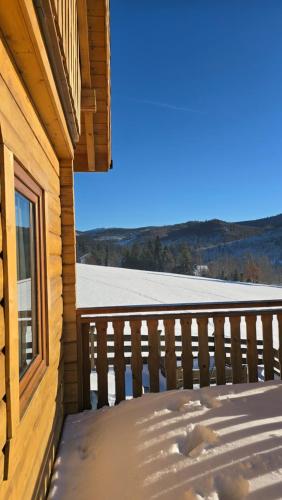 a balcony of a log cabin with snow on the ground at Hasiorówka Dom w górach z jacuzzi w cenie in Złatna