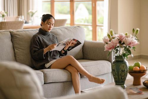 a woman sitting on a couch reading a magazine at Life Resort Quy Nhon in Quy Nhon