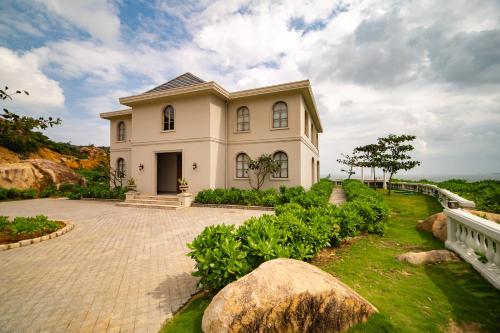 a large white house with a stone driveway at Life Resort Quy Nhon in Quy Nhon