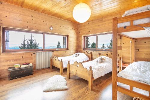 two beds in a room with wooden walls and windows at La Perchette - Joli chalet classé 3 étoiles in Chamrousse