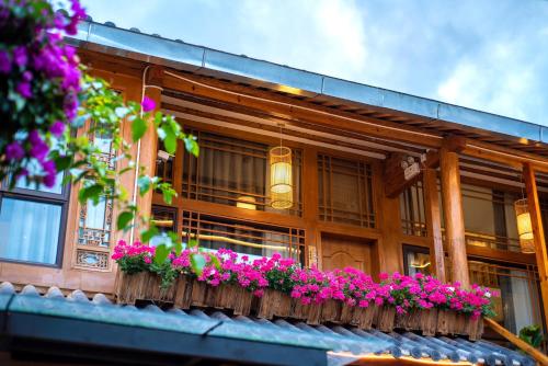 a building with a balcony with flowers on it at Lijiang Lights Quiet Garden Desinger SerenityHaven Hotel B&B Gucheng Zhongyi Mufu Branch in Lijiang