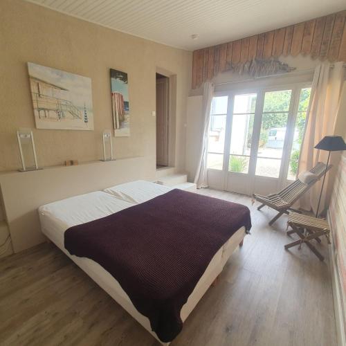 une chambre avec un lit, une chaise et une fenêtre dans l'établissement Villa soulacaise - 3482, à Soulac-sur-Mer