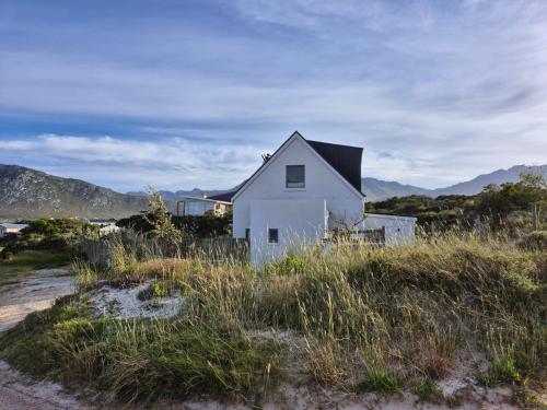 a white house sitting on top of a beach at The Dunes Pringle Bay in Pringle Bay