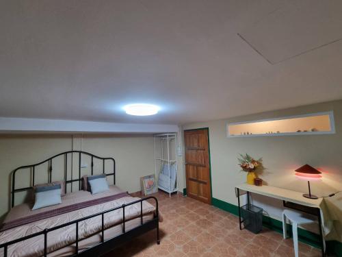 a bedroom with a bed and a desk with a lamp at Kanlayana Hostel in Ban Bang Toei (1)