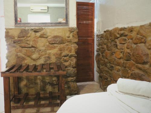 a bedroom with a stone wall and a mirror at Barn Guesthouse in Kroonstad