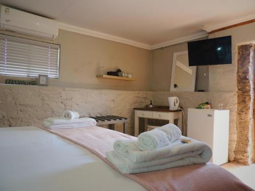 a bedroom with towels on a bed and a kitchen at Barn Guesthouse in Kroonstad