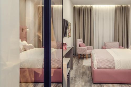 a hotel room with two beds and a chair at Hotel Dirista in Shkodër