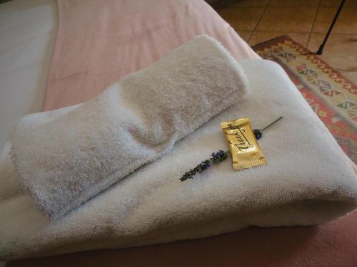 a white towel with a gold brooch on a bed at Barn Guesthouse in Kroonstad