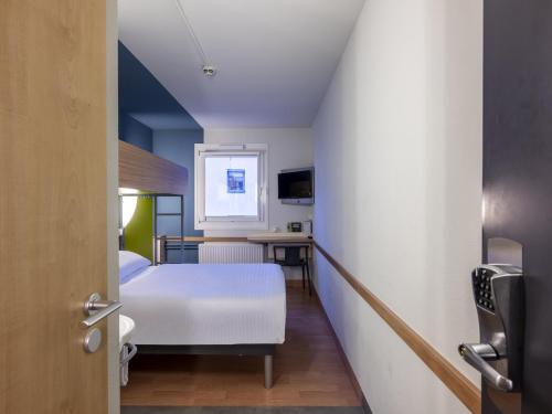 a small room with a bed and a desk at B&B HOTEL Dortmund-Airport in Holzwickede