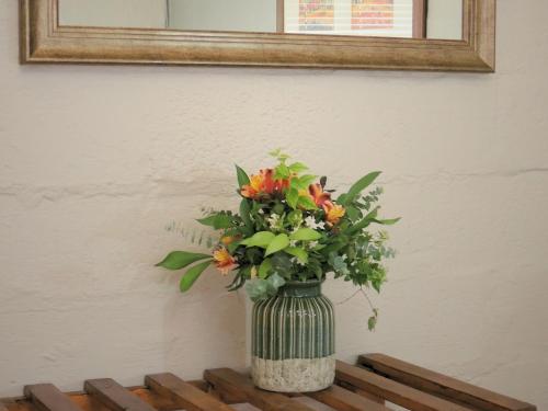a vase of flowers sitting on a table under a mirror at Barn Guesthouse in Kroonstad